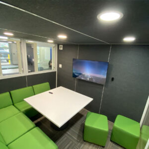 Green couch in a office pod with a tv